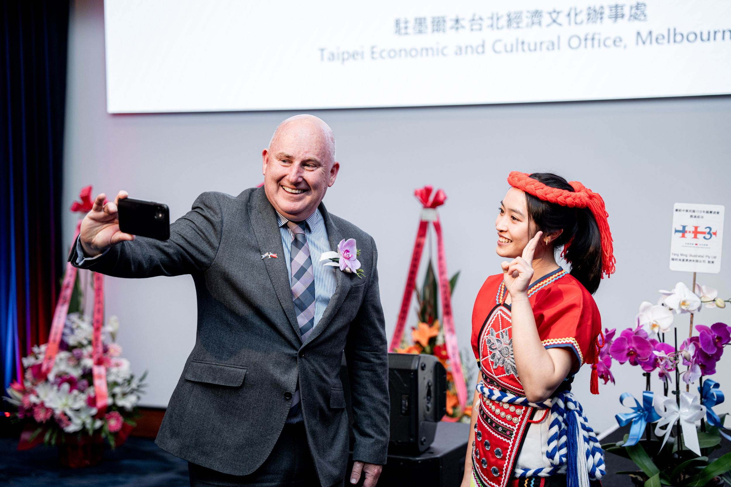 Cultural celebration event with traditional attire and decorative floral arrangements.