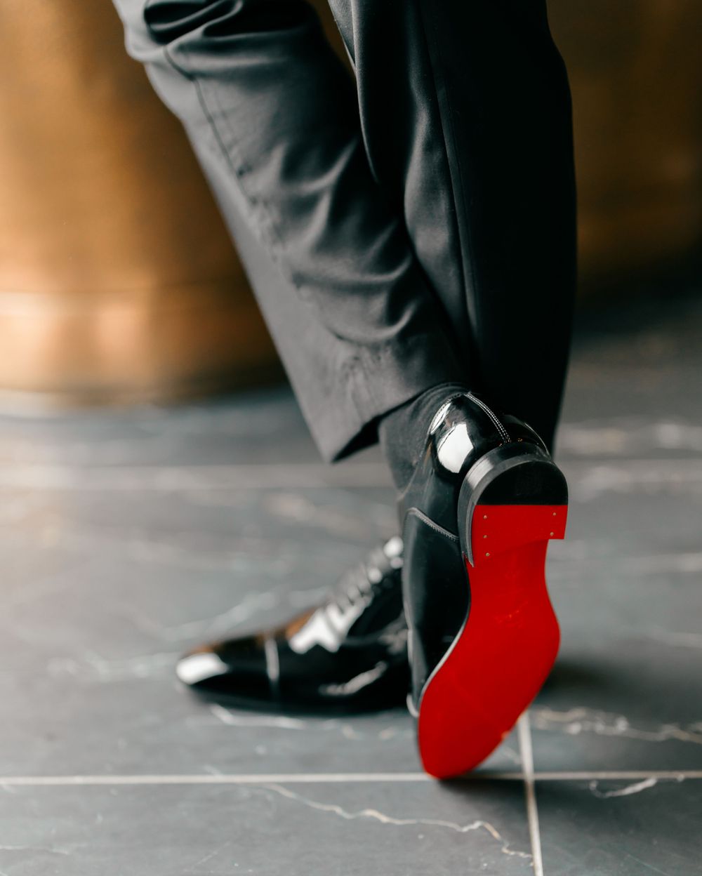 Close-up of formal black patent leather shoes with distinctive red soles.