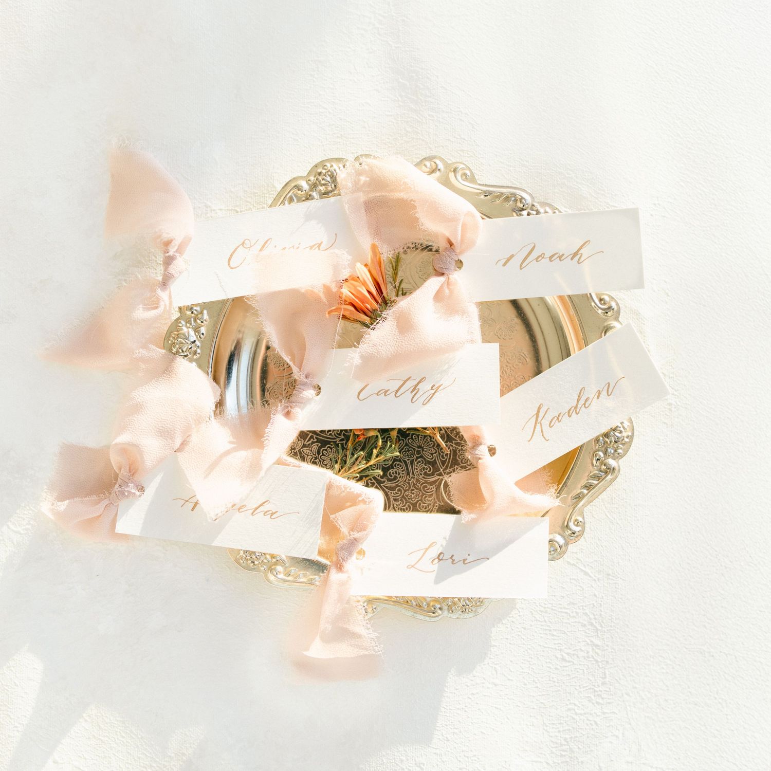 Delicate peach ribbon name cards with calligraphy for wedding place settings.
