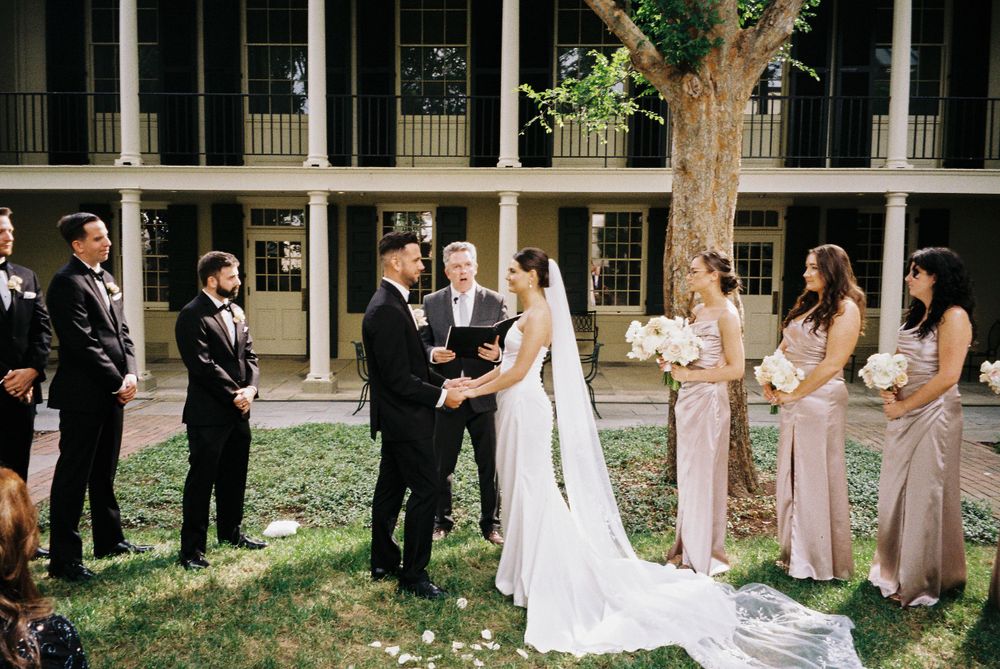 An outdoor wedding ceremony with wedding party members in formal attire.