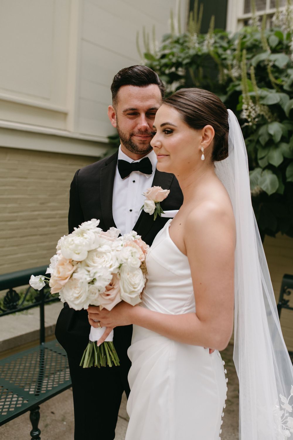 A romantic wedding portrait featuring a couple with a lush bouquet of white roses.