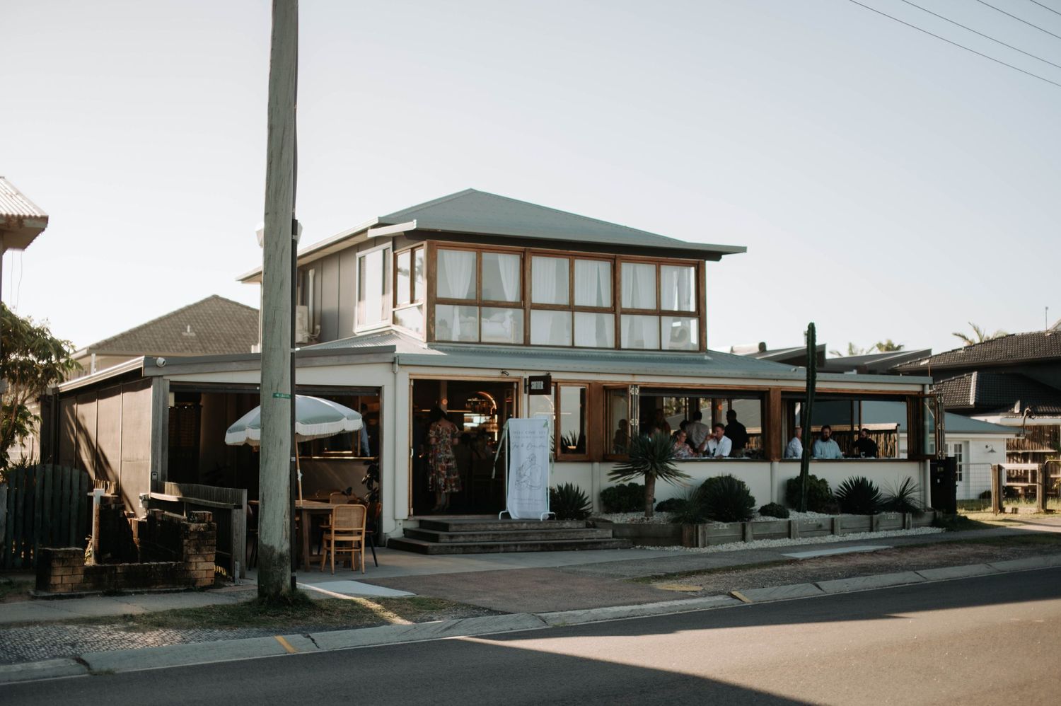 Modern two-story coastal building with large windows and outdoor seating area.