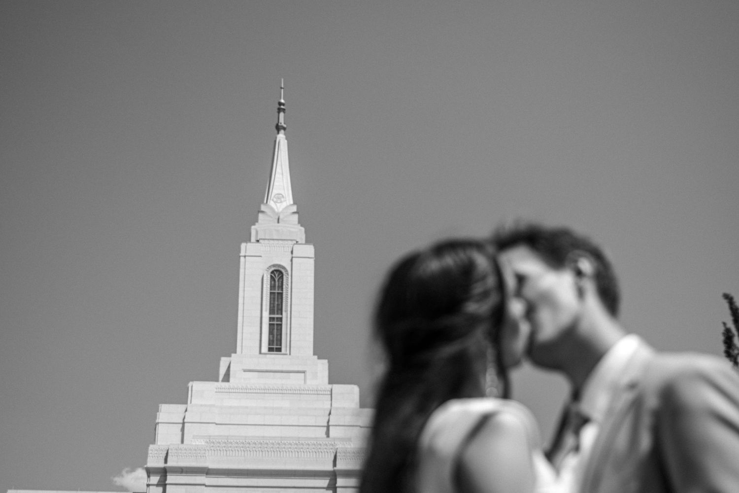 Couple kissing in front of Orem temple on wedding day.