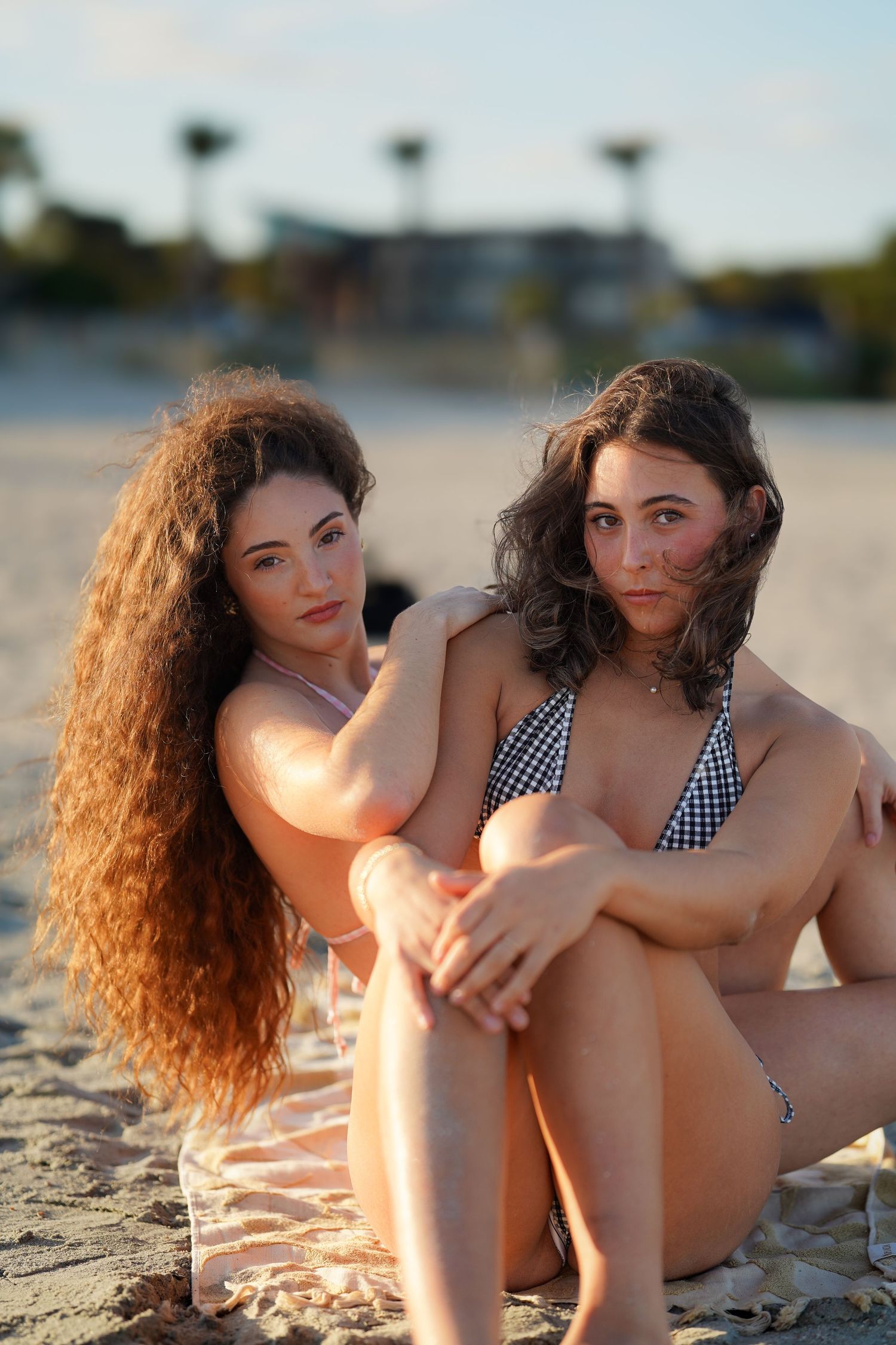 Two friends relaxing on a sunny beach in swimwear during sunset.