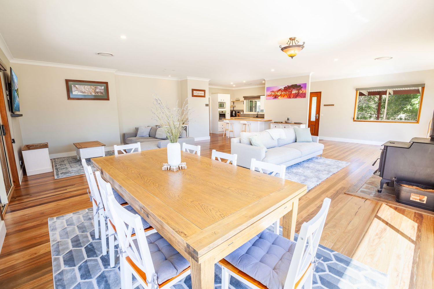 Modern open-plan dining area with wooden table and chairs in a bright, sunlit room.