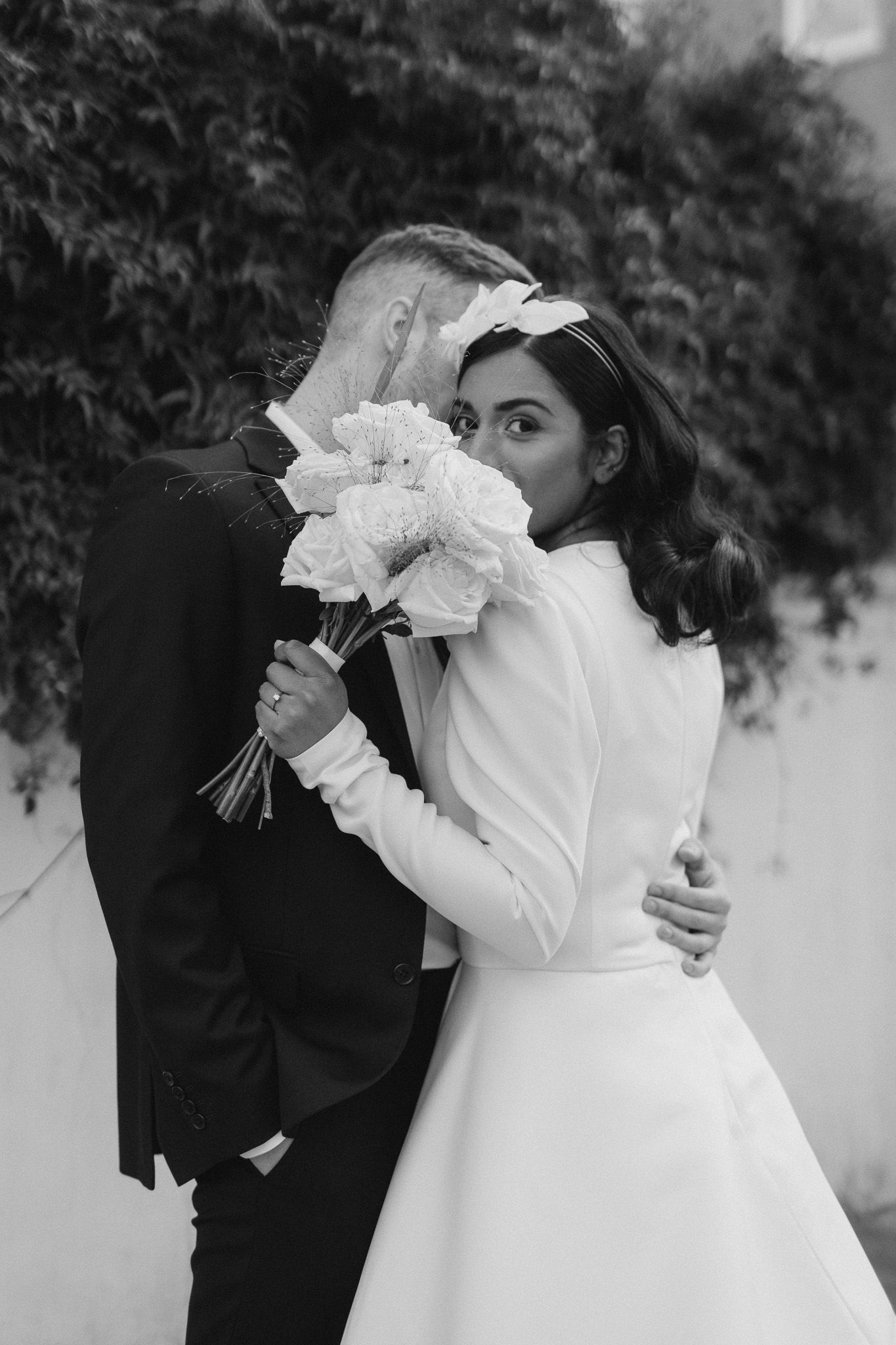 A bride in a classic white dress poses with her bouquet beside her partner.
