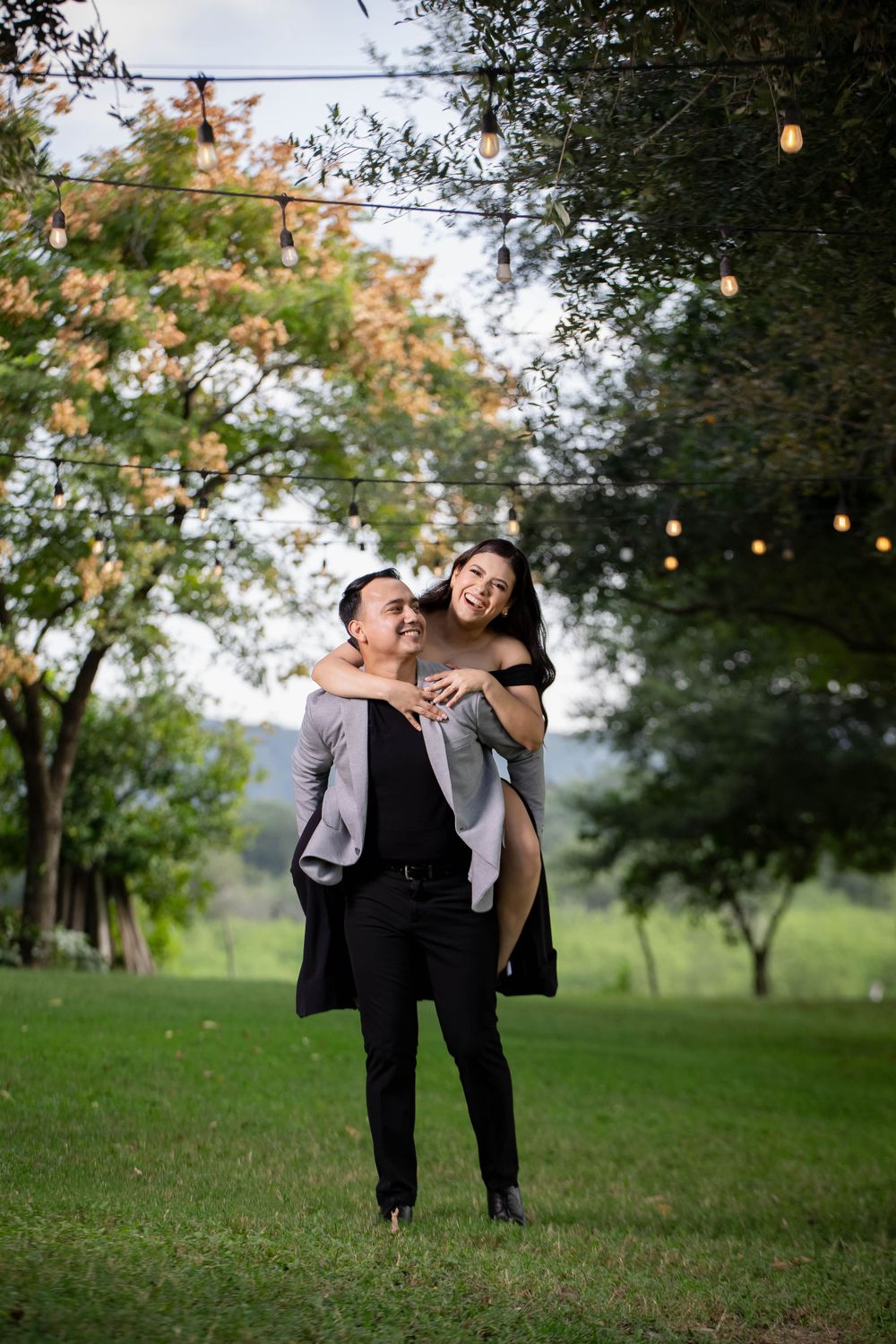 A joyful piggyback moment captured outdoors under string lights and trees.