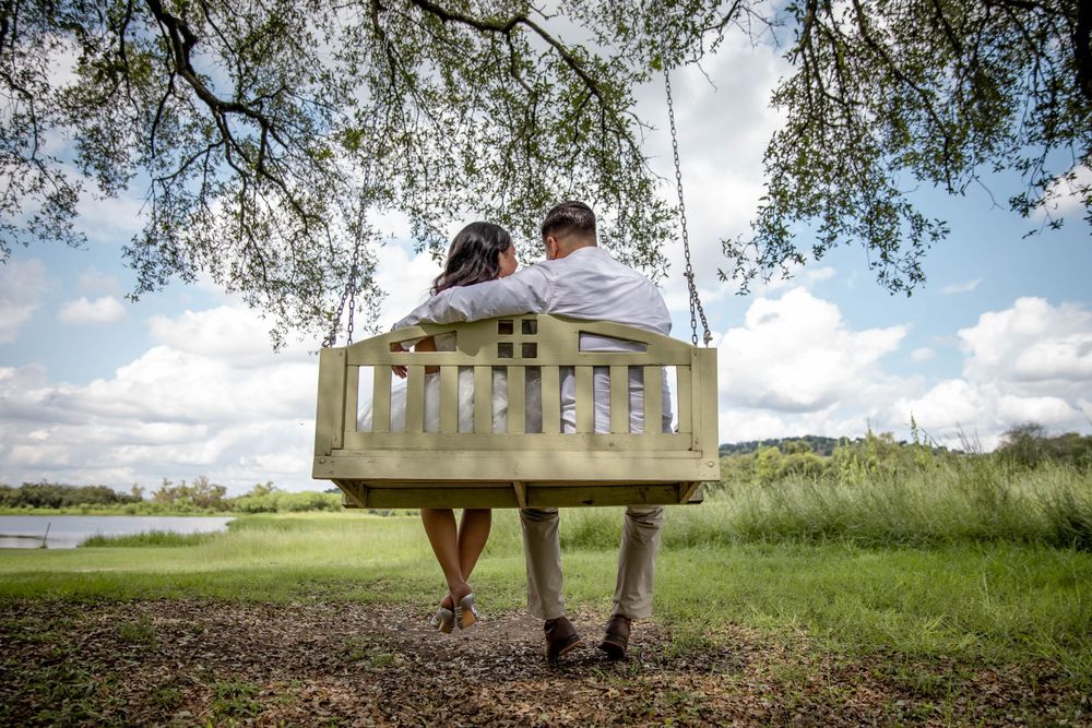 A wooden porch swing overlooking a scenic lake view on a sunny day.