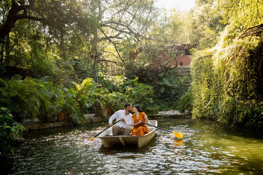 A romantic boat ride through a lush garden pond with overhanging trees and golden sunlight.