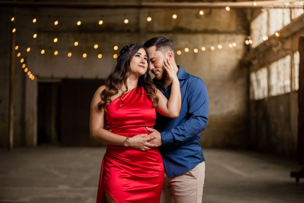 Intimate moment captured in industrial space with string lights creating romantic ambiance.