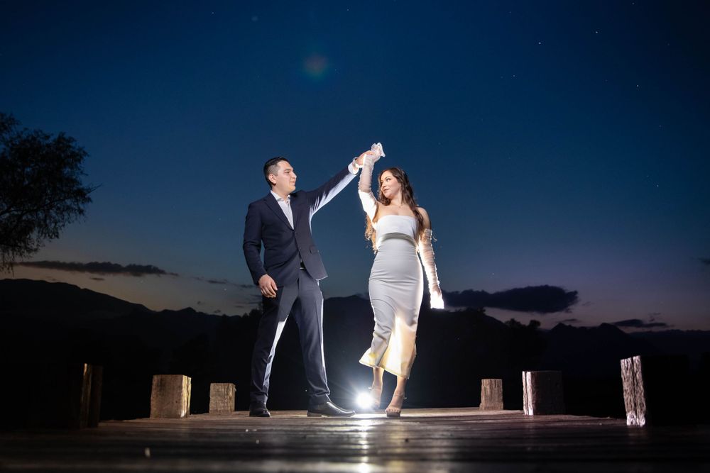Dancing couple illuminated by spotlight against dark blue evening sky.