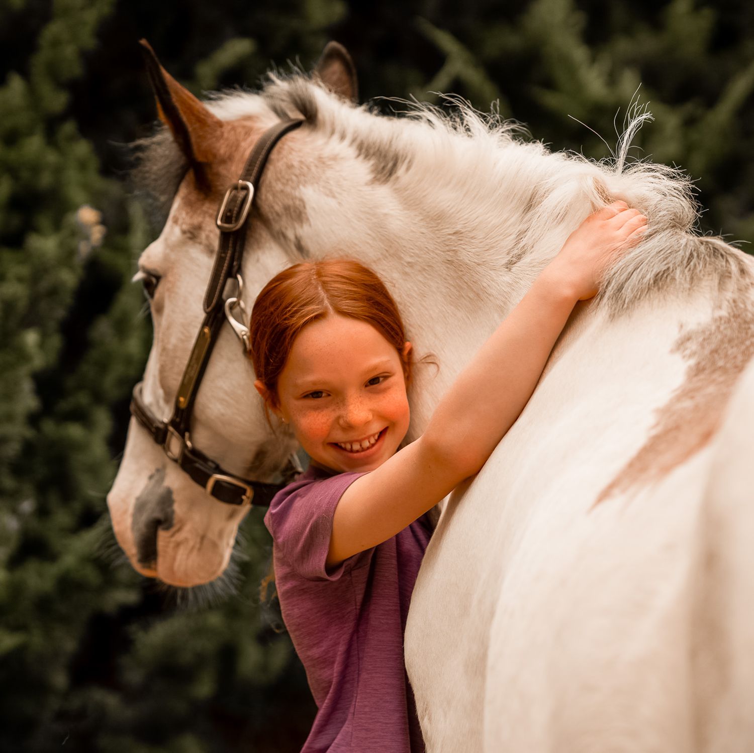 Young girl hugging white horse showing pure joy and connection with the animal.