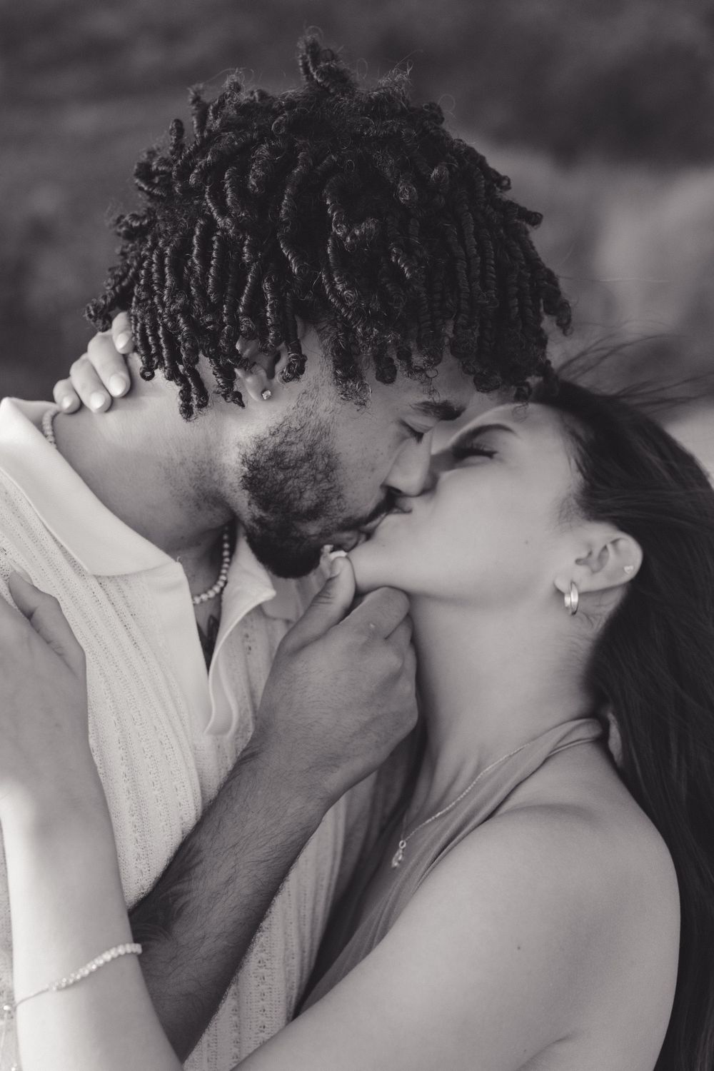An intimate black and white portrait of a couple sharing a romantic kiss.