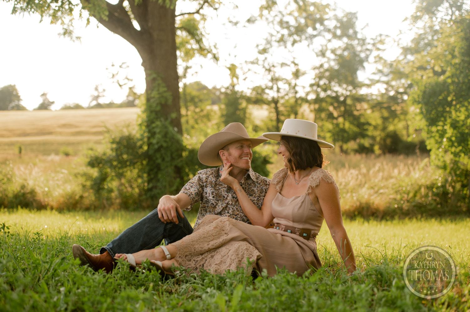 A romantic countryside photoshoot with a couple lounging in golden hour light under a tree.