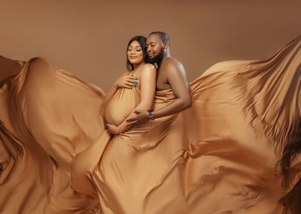 Artistic maternity photo with flowing copper fabric creating dramatic movement.