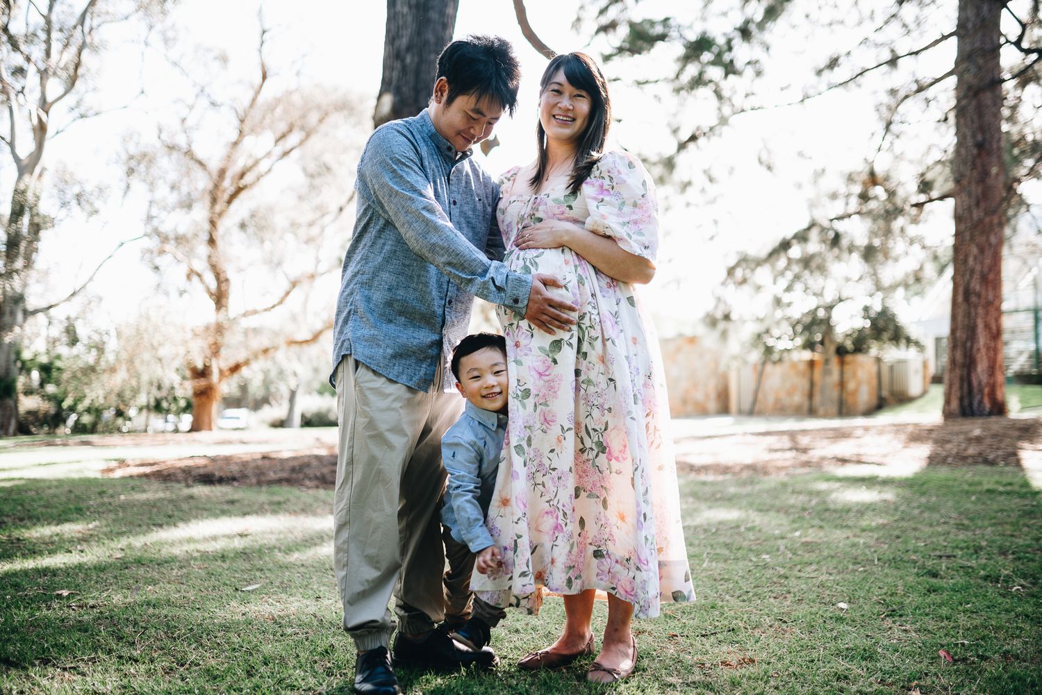 A couple spending time together on a sunny day in a park among trees on green grass taken by Melbourne maternity and family photographer.