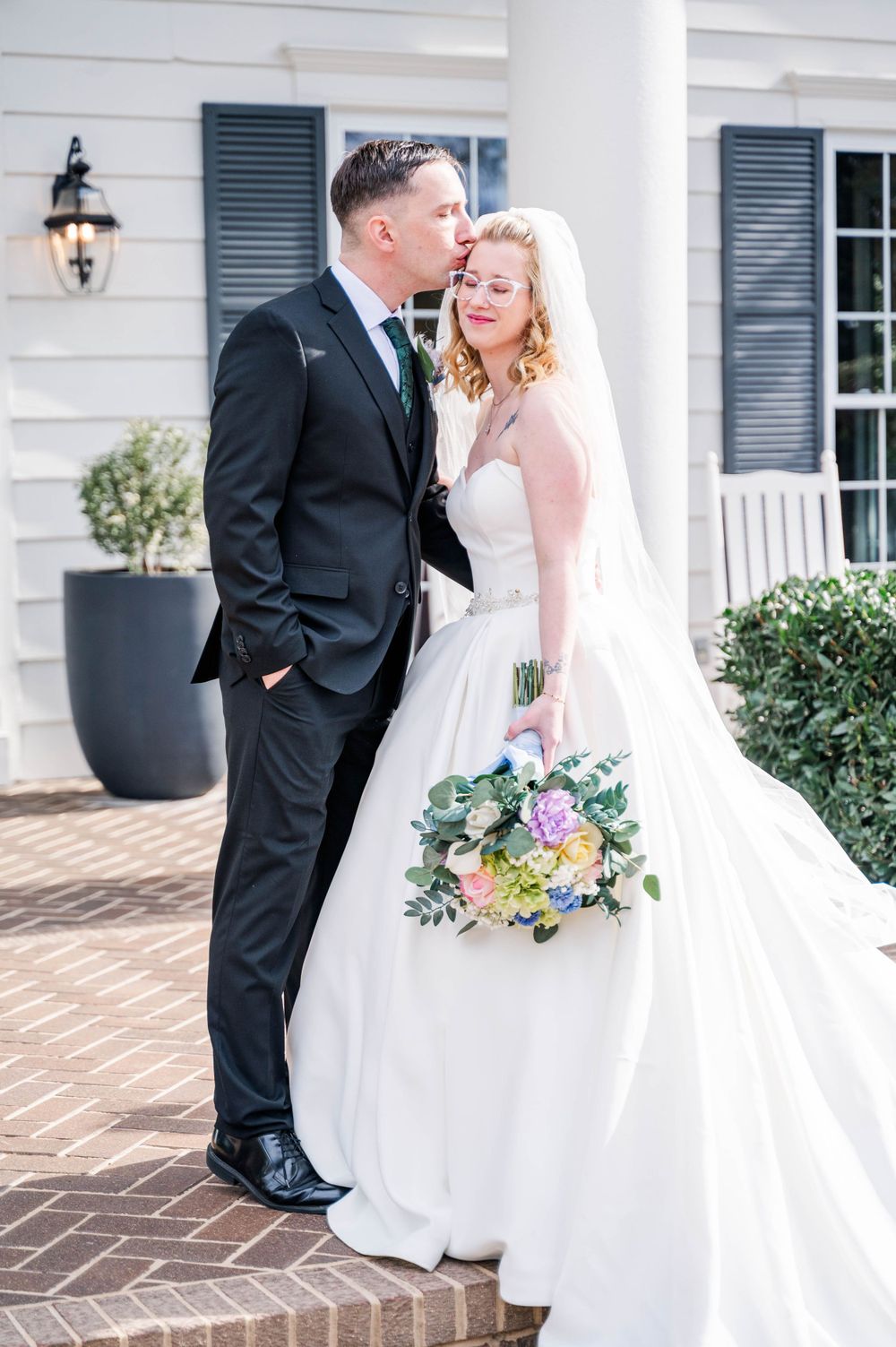 Intimate wedding moment on brick porch with spring bouquet. The Highgrove Estate, Fuquay-Varina, NC