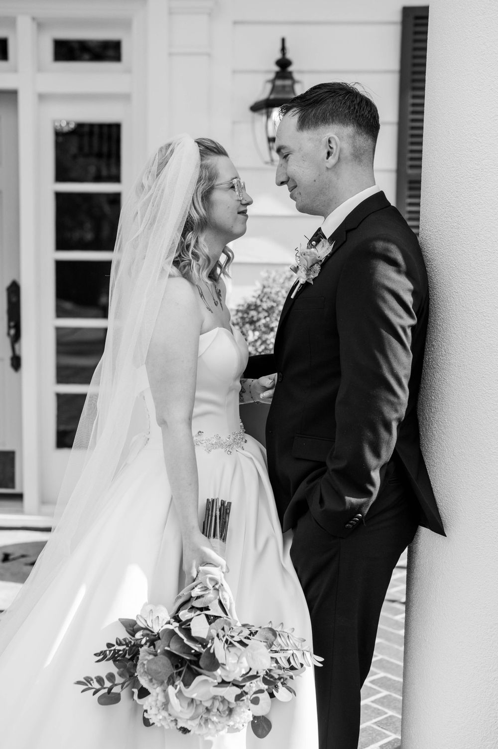 Black and white intimate wedding portrait against white colonial architecture. The Highgrove Estate, Fuquay-Varina, NC
