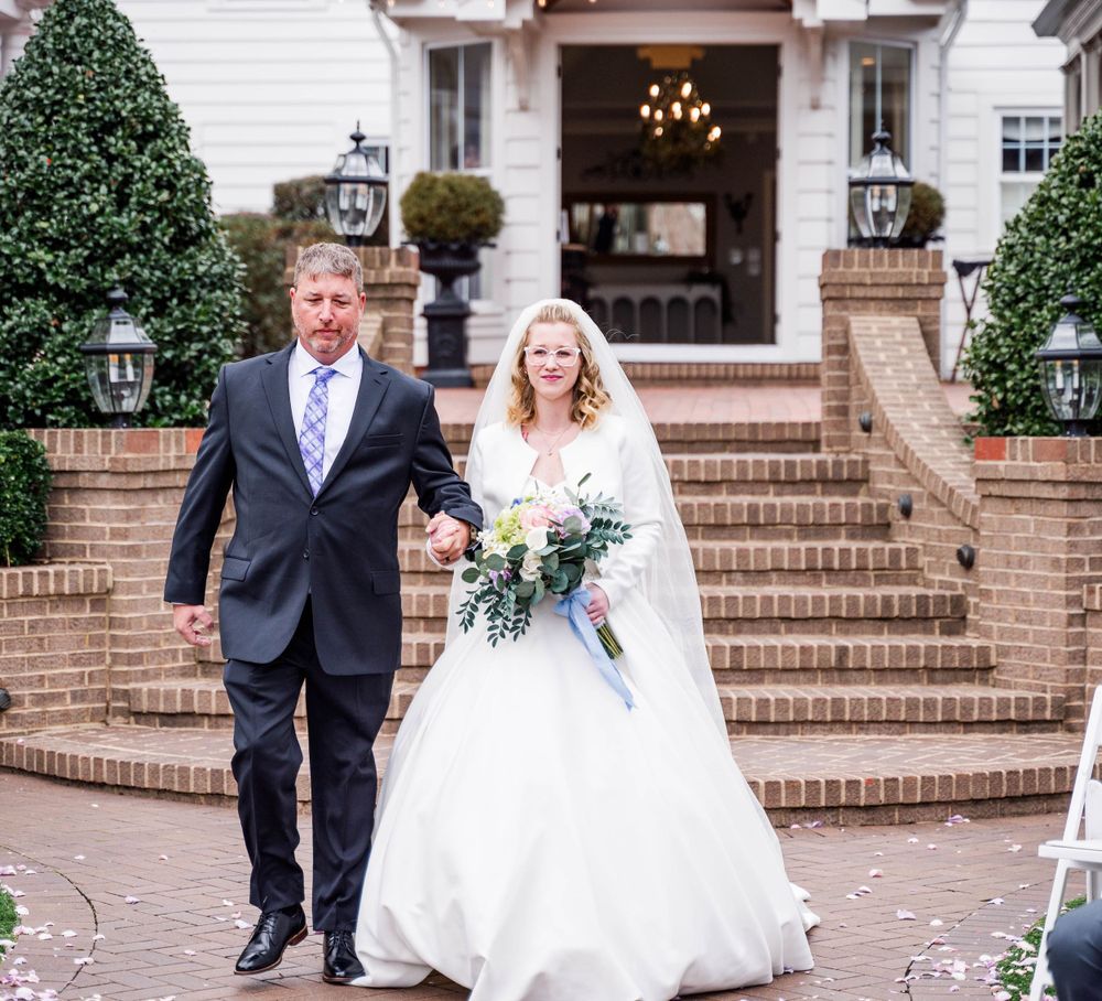 Couple descending elegant brick stairs of white mansion after wedding ceremony.