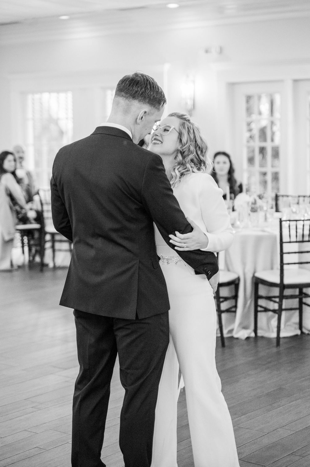Black and white photo of couple dancing in an elegant reception hall.