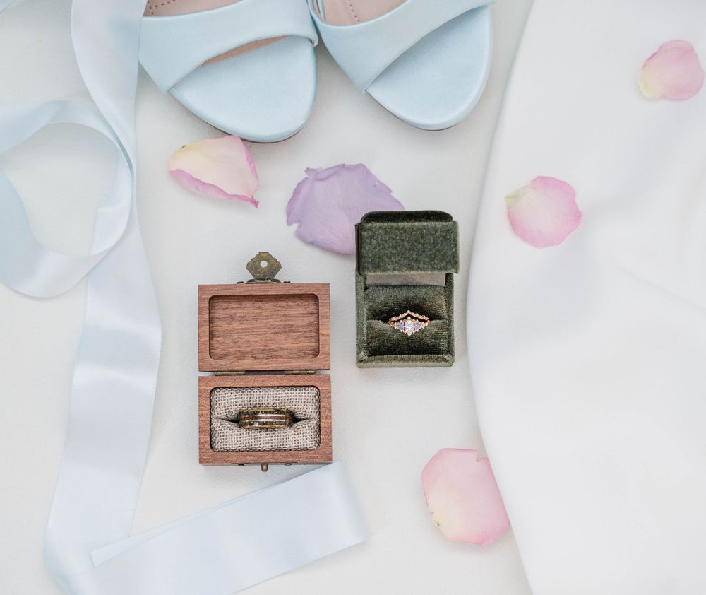 Vintage wooden ring boxes with engagement rings displayed with pale blue wedding shoes.
