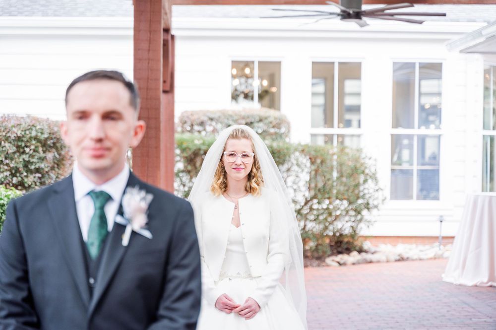 A wedding ceremony scene with a brick house backdrop and outdoor decor. The Highgrove Estate, Fuquay-Varina, NC