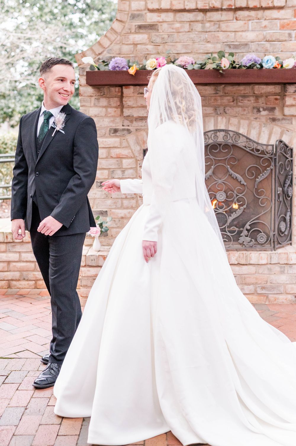 Elegant wedding portrait in front of a decorative brick fireplace with floral mantle.