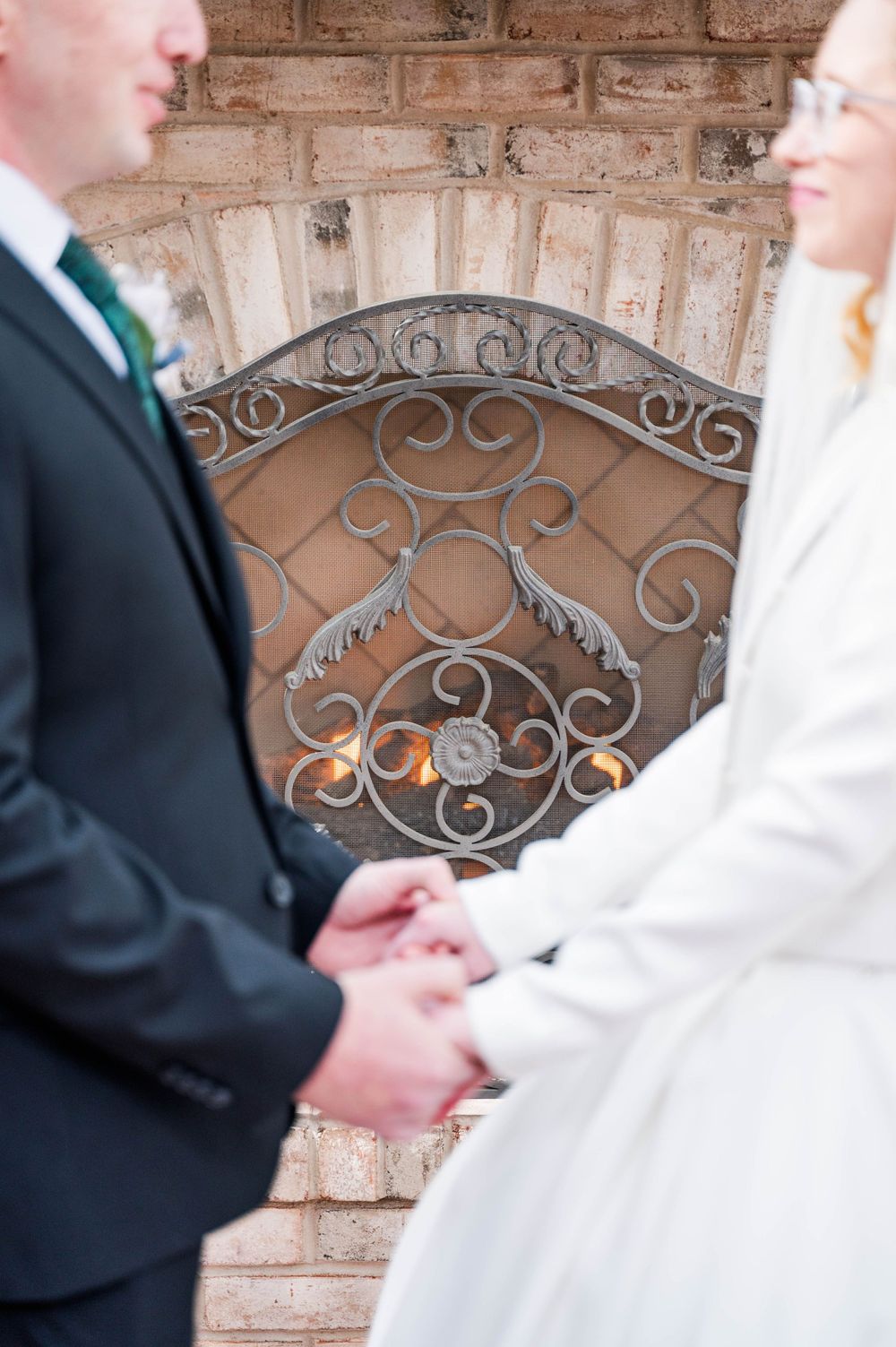 Close-up of joined hands against ornate wrought iron fireplace screen. The Highgrove Estate, Fuquay-Varina, NC
