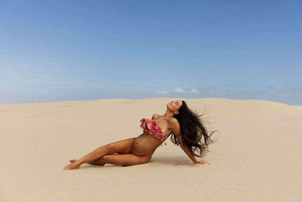 Maternity photo on sand dunes with subject reclining dramatically.