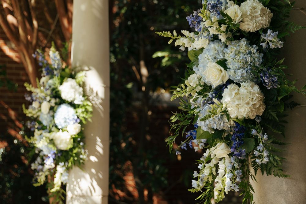 White and blue floral arrangements with hydrangeas decorating an outdoor wedding venue.