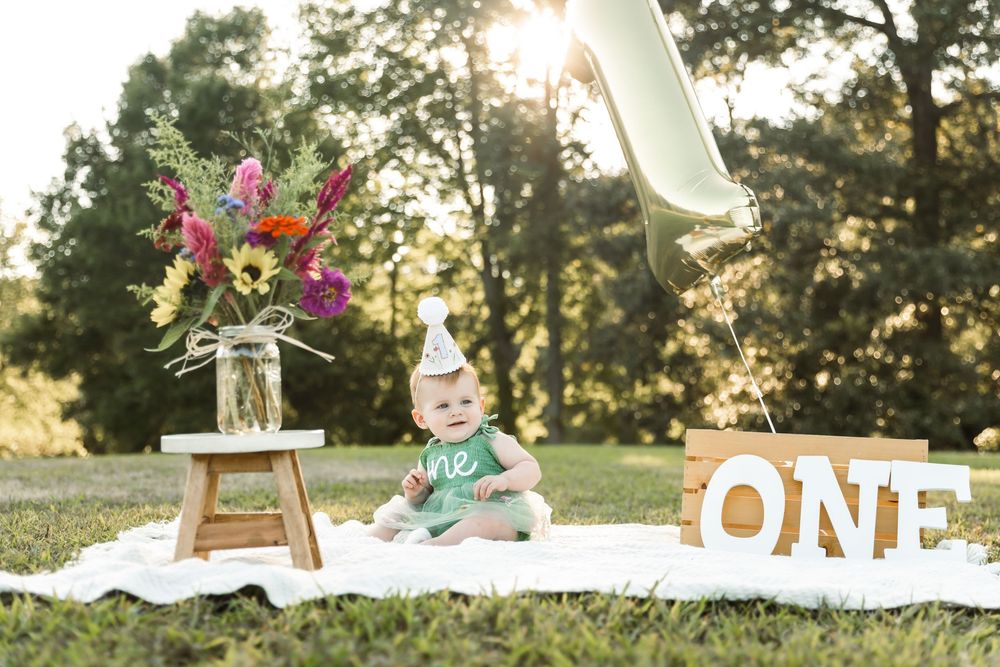 First birthday celebration setup outdoors with decorative letters and floral arrangements.