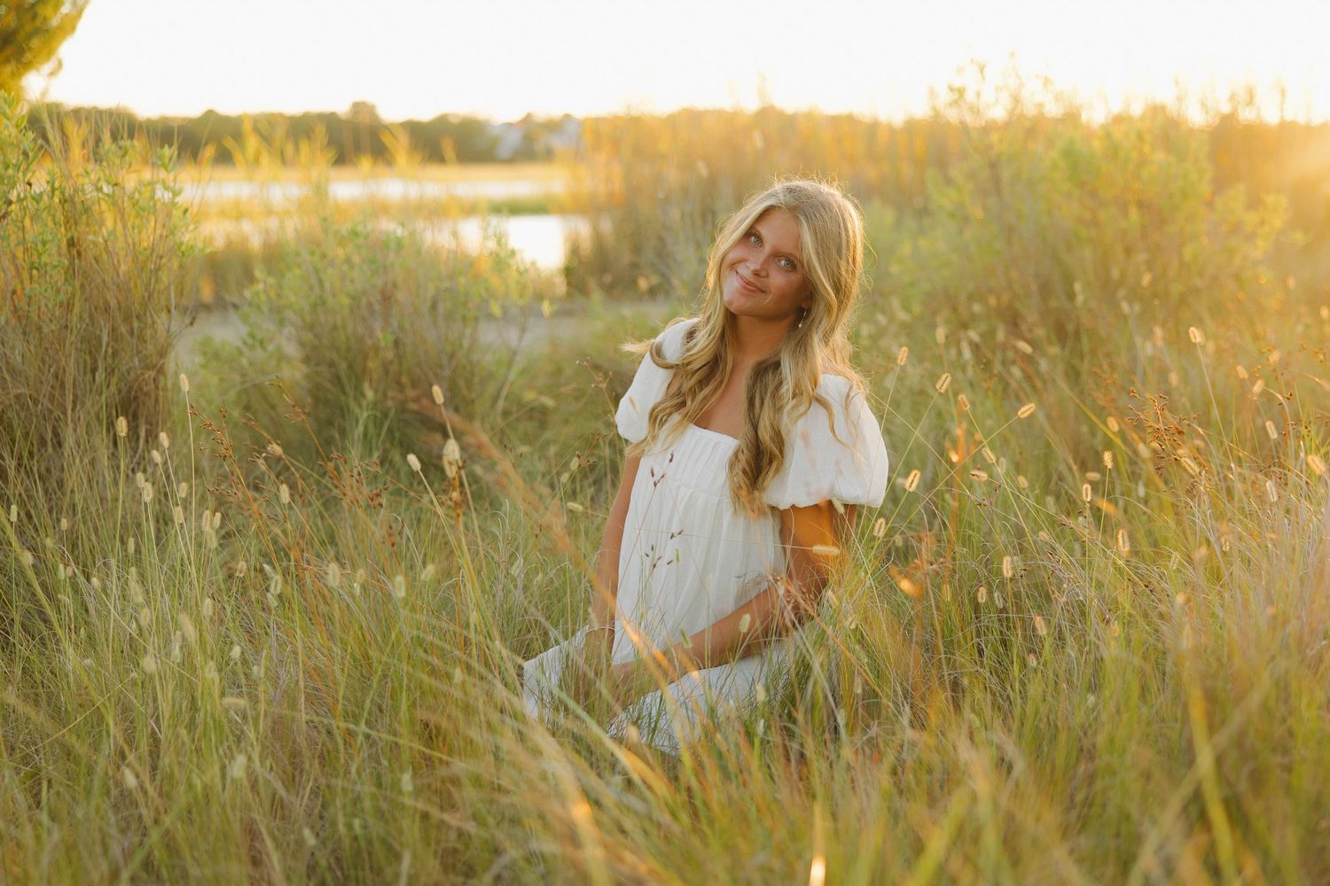 Whimsical portrait in purple top and blue skirt under golden sunlit tree branches.