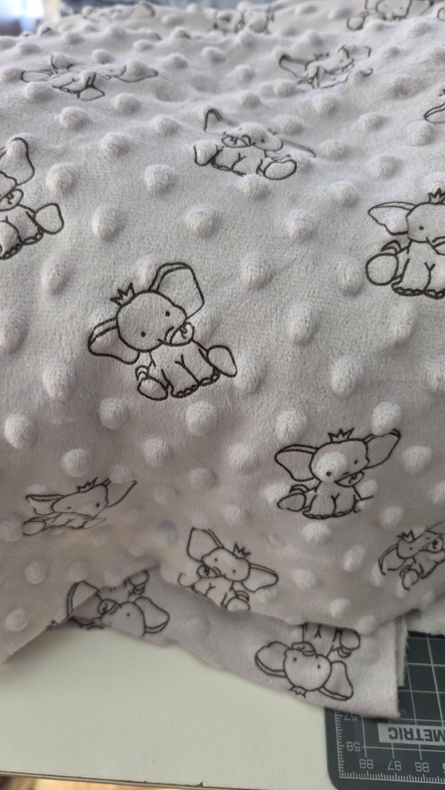 White minky dot fabric with cute elephant print pattern, perfect for baby blankets and soft nursery accessories.