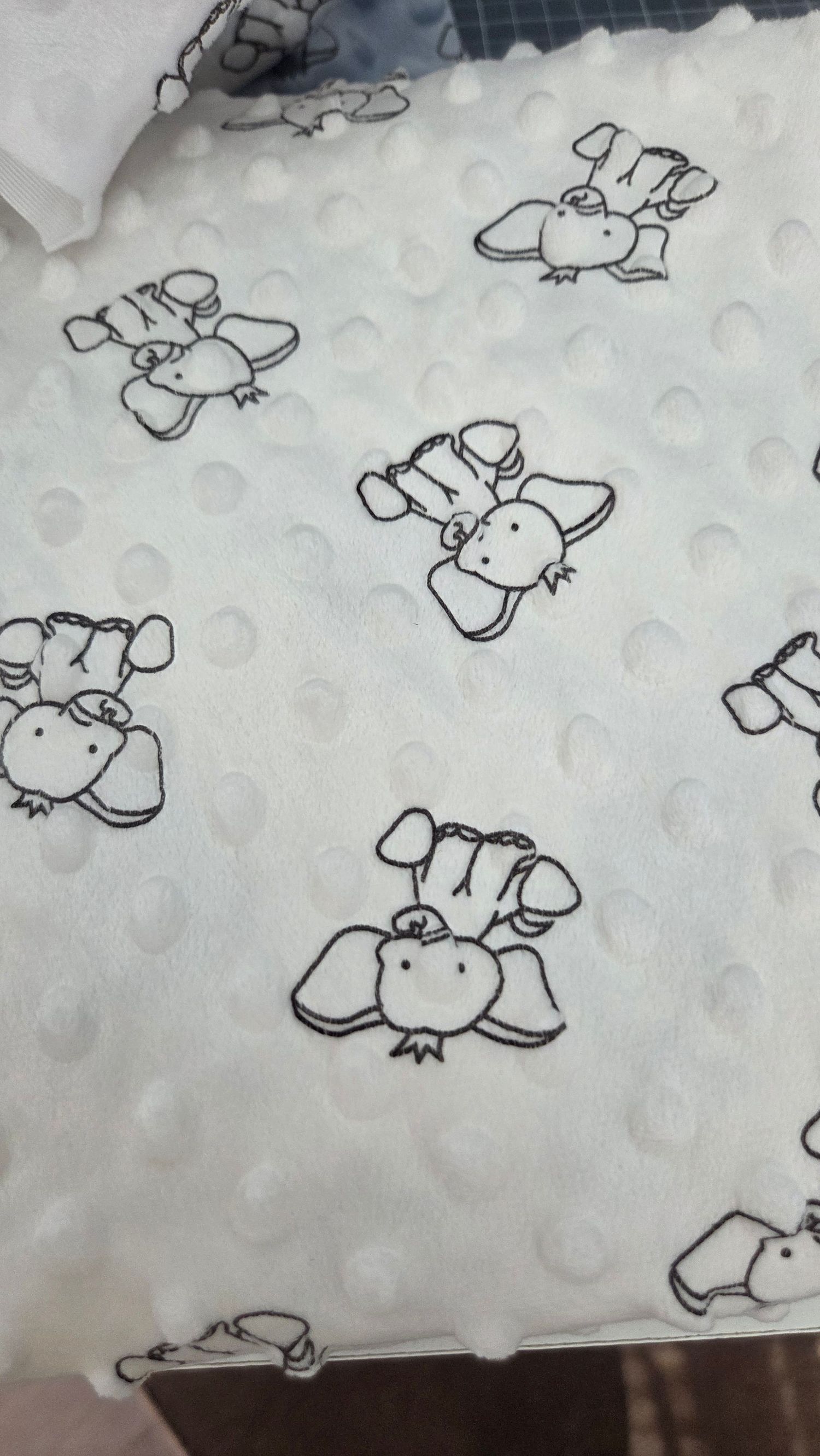White minky dot fabric with black outline elephant print pattern, perfect for baby blankets and nursery items.