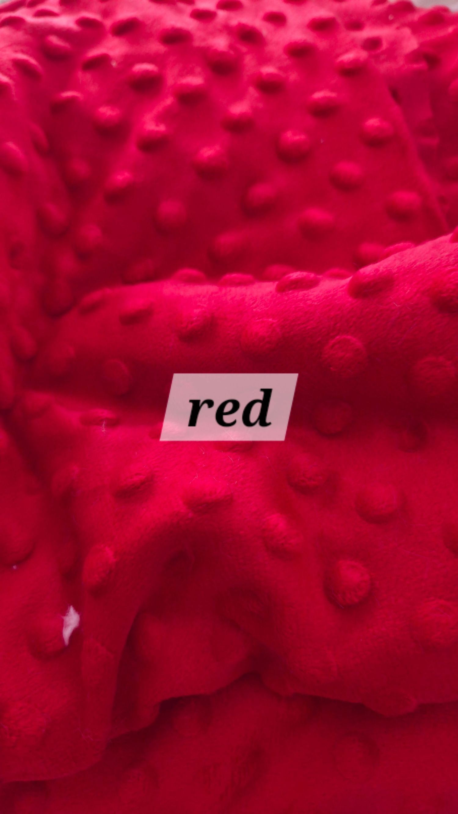 Close-up of red bumpy minky fabric texture with a bold red color label overlay.