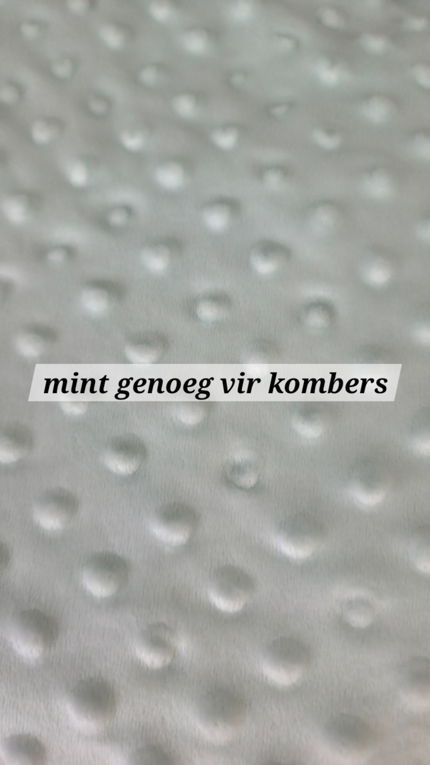 Close-up of mint green dimple dot minky fabric texture, soft and plush, ideal for blankets and comfort items.
