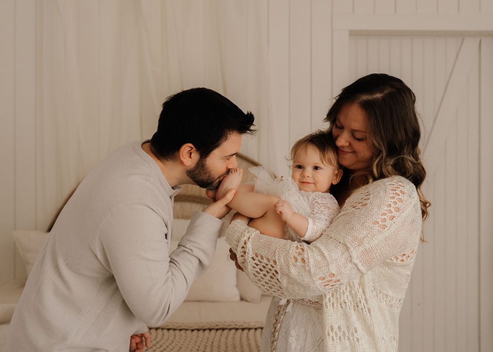 Family sharing intimate moment in white room with neutral decor.