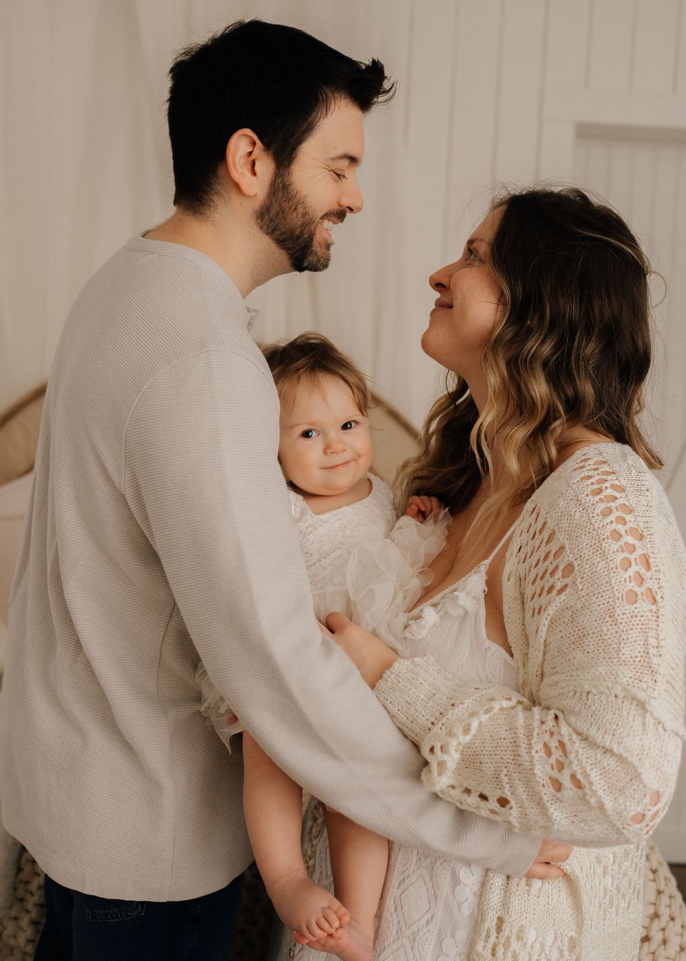 Family sharing joyful moment together in neutral studio setting.