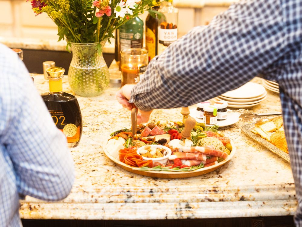 Someone reaching for a slice of fresh pizza topped with tomatoes and herbs on a rustic wooden table with flowers in a vase.