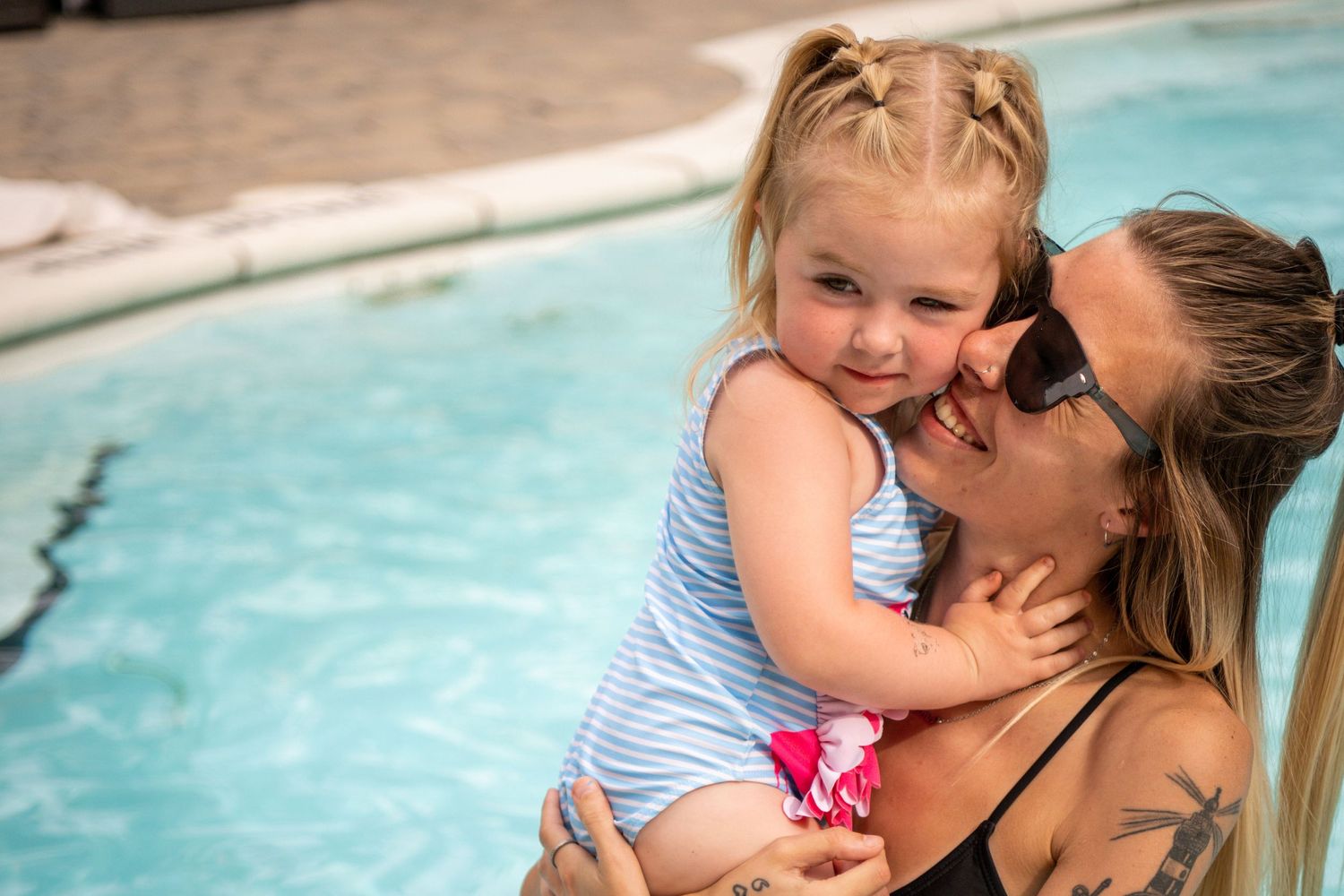 A joyful poolside moment shared between two people in swimwear on a sunny summer day.