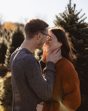 An intimate moment shared between two people in a Christmas tree farm.