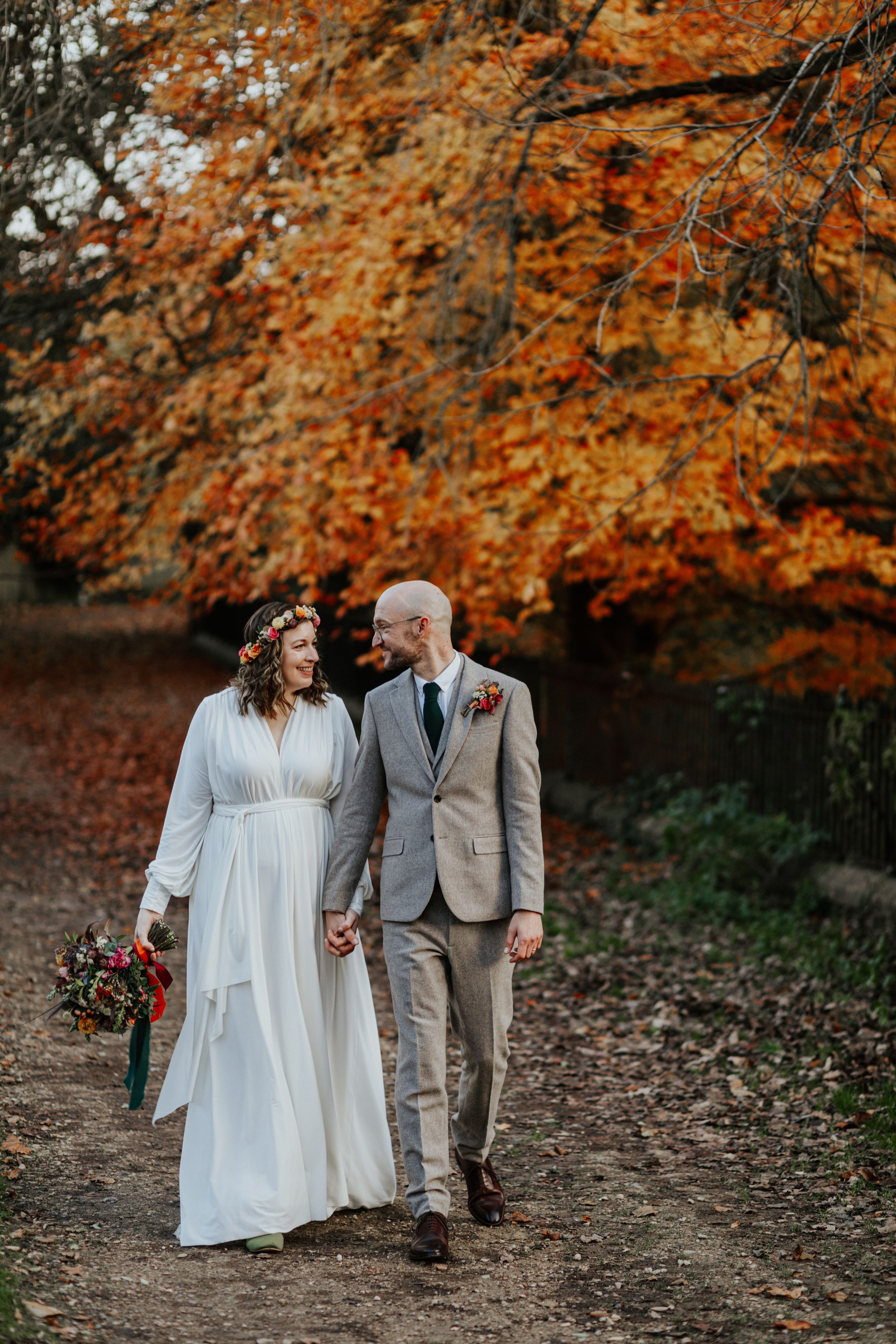 Candid wedding couple portrait with golden autumn leaves in the background.