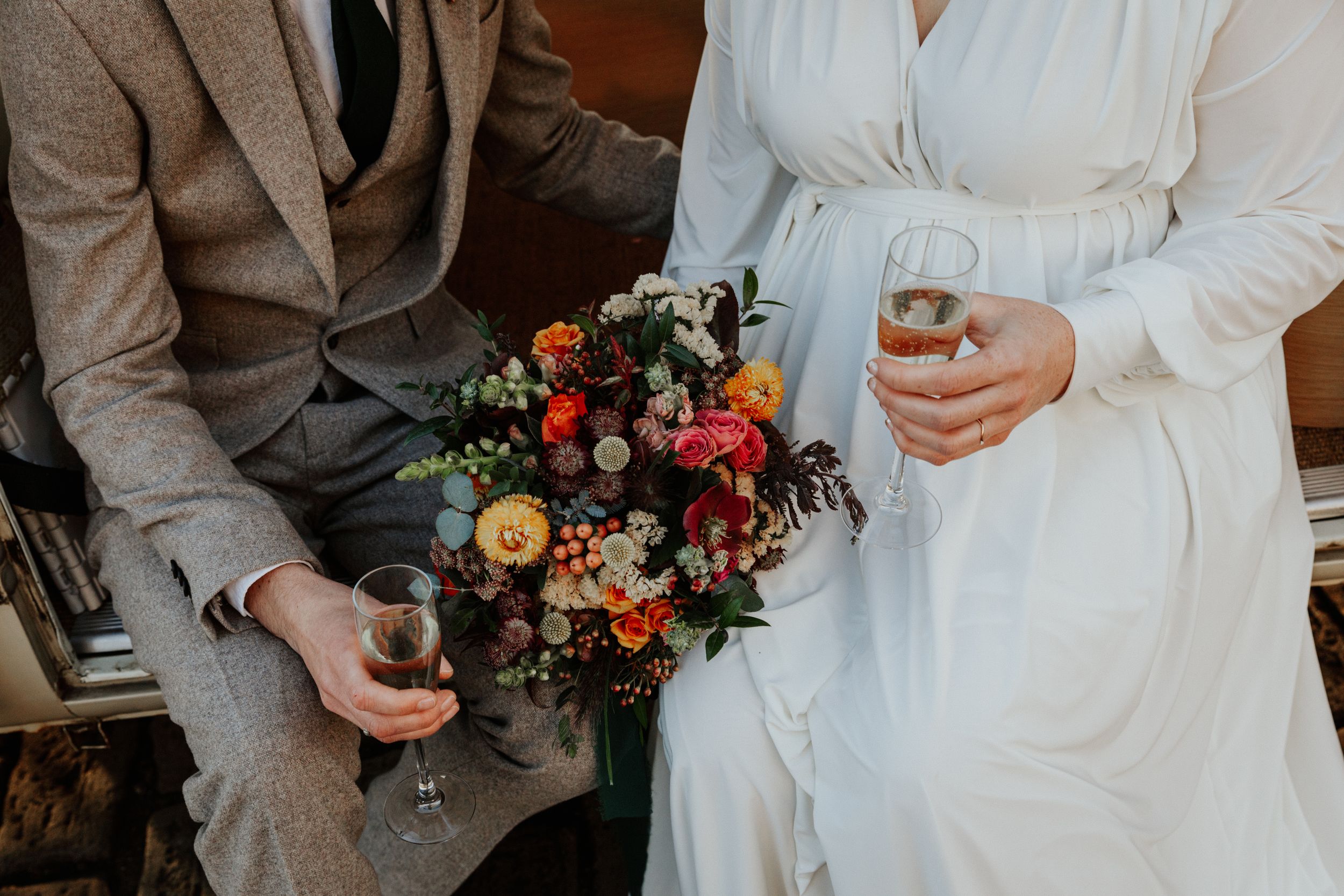 details shots of bride and groom holding drink , flowers in Bath city during golden hour