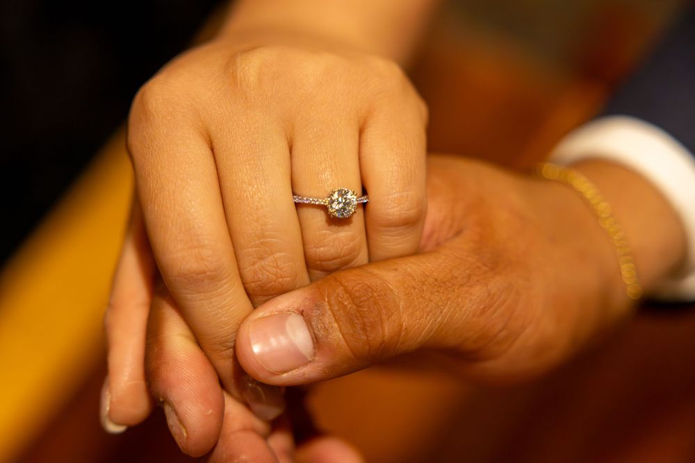 Close-up shot of hands displaying an elegant diamond engagement ring.