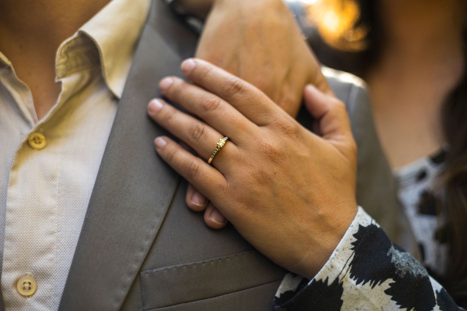 Close-up shot of hands adjusting a gray suit jacket button.