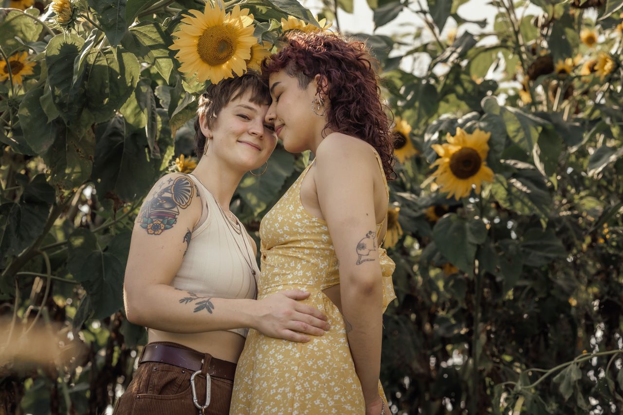 Couple embracing in sunflower field during golden hour photoshoot.