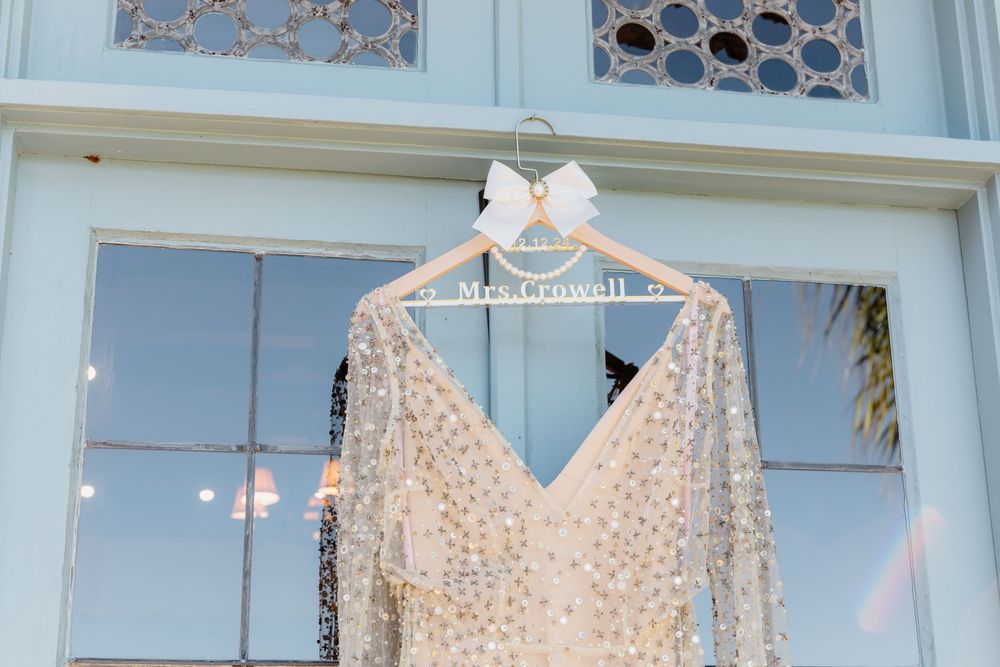A clothing store displays a row of white polka dot dresses on hangers against a light blue wall.