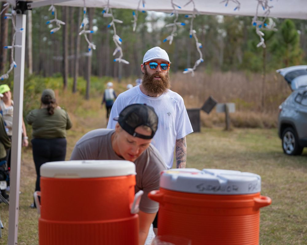 Aid station setup with orange water coolers under decorated tent canopy.