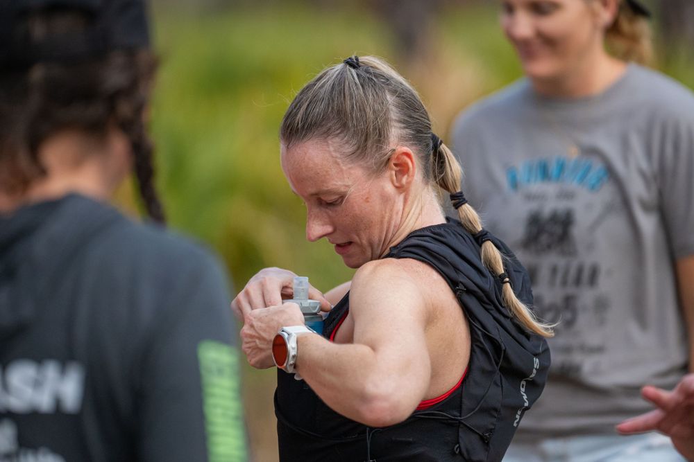 Trail runner adjusting gear at outdoor event aid station.