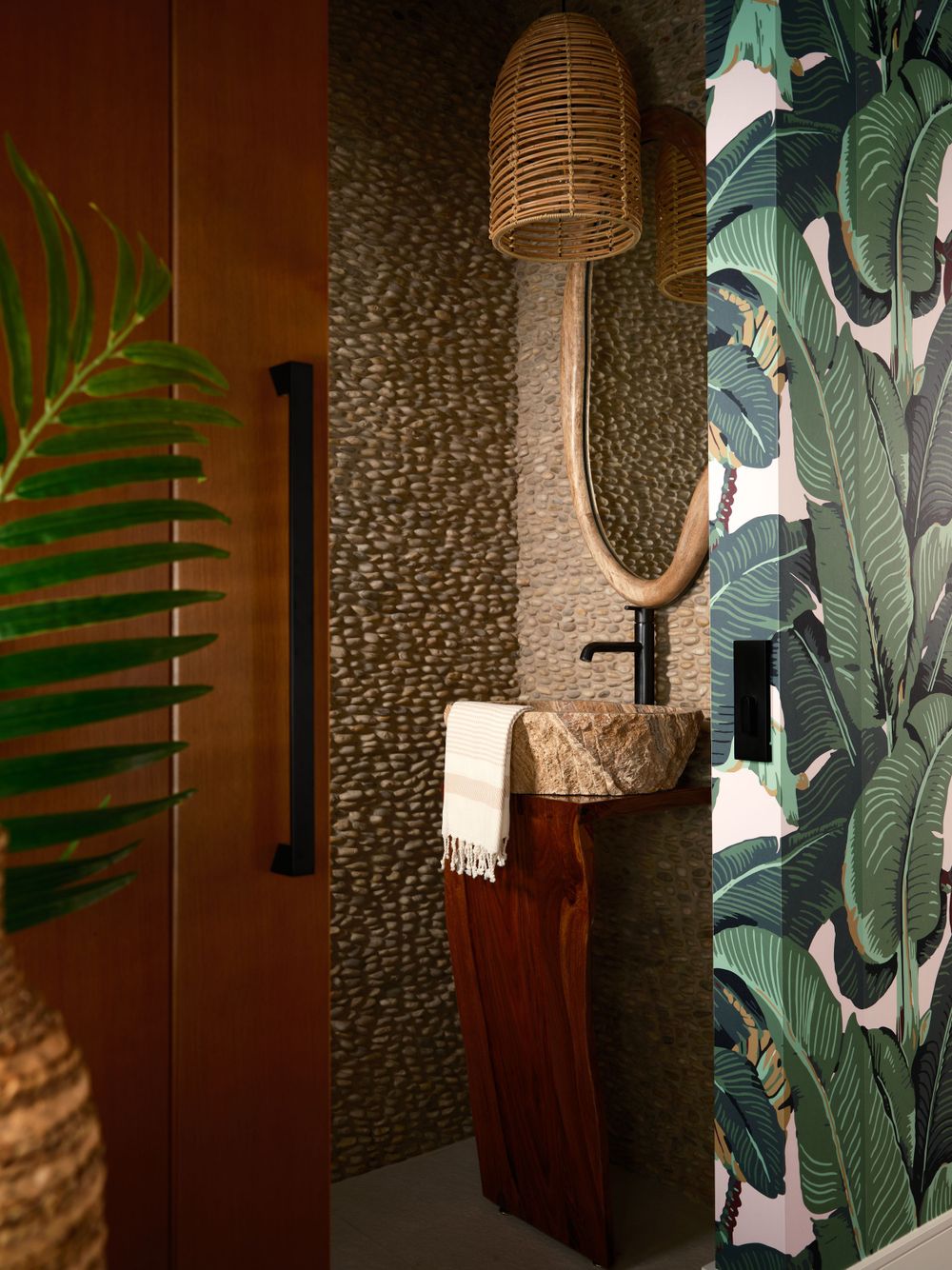Eclectic powder room with tropical wallpaper, textured tile, and moody lighting — photographed by Khoi Ly.